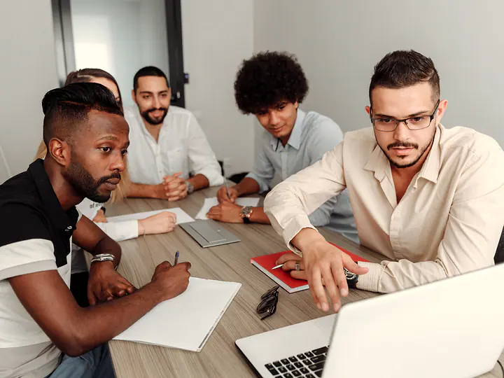 A team reviewing documents and a laptop together at a table.