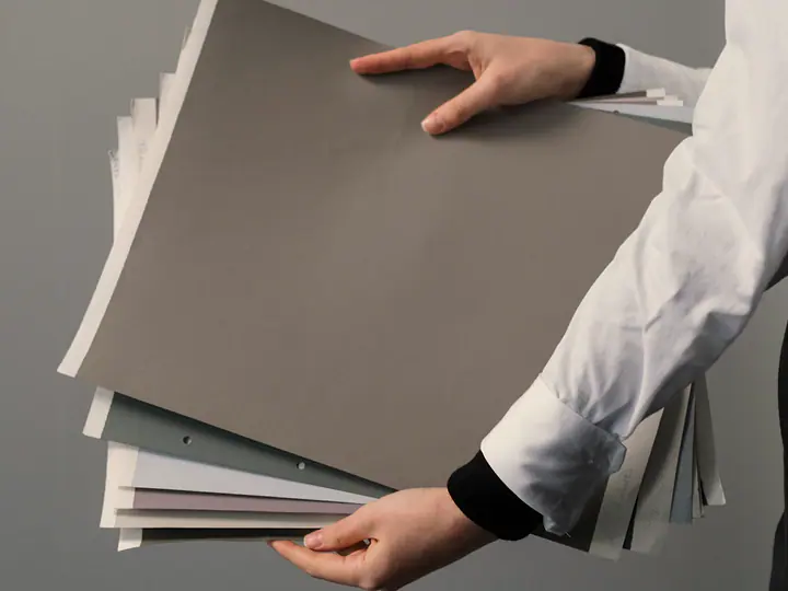 Hands holding a stack of coloured document folders.