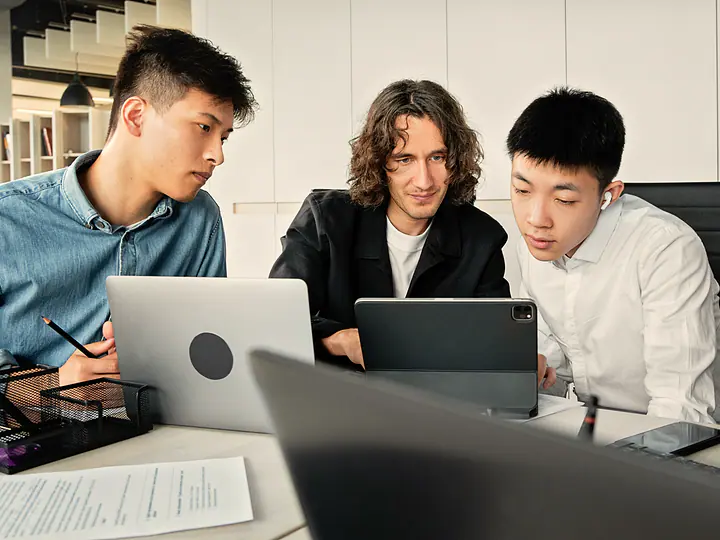 Three people working side by side on laptops.