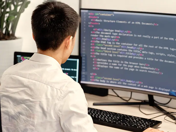 A developer at a desk reading markup on a large monitor.